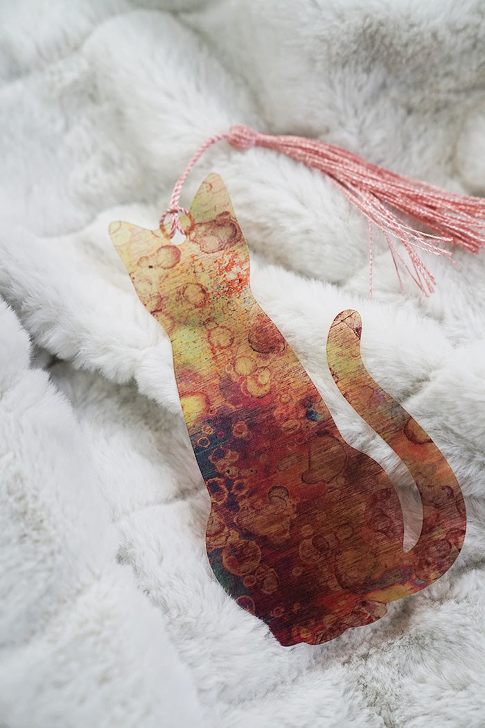 Cat-shaped decorative item with a tassel on a textured white surface