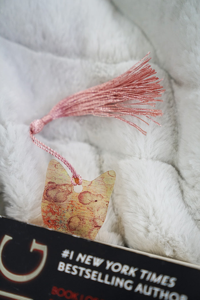 Cat-shaped bookmark on an open book with a soft textured background