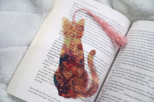 Cat-shaped bookmark on an open book with a soft white background