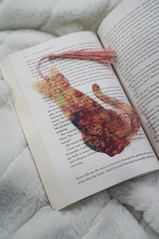 Cat-shaped bookmark on an open book with a soft textured background