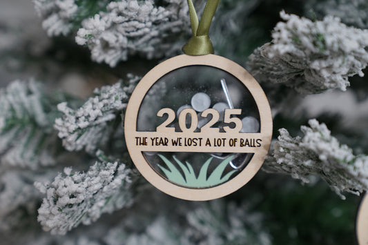 Ornament with '2025 The Year We Lost a Lot of Balls' text on a Christmas tree.